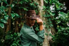 Man in forest wearing brown hat.