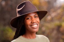 Smiling person wearing a hat outdoors.