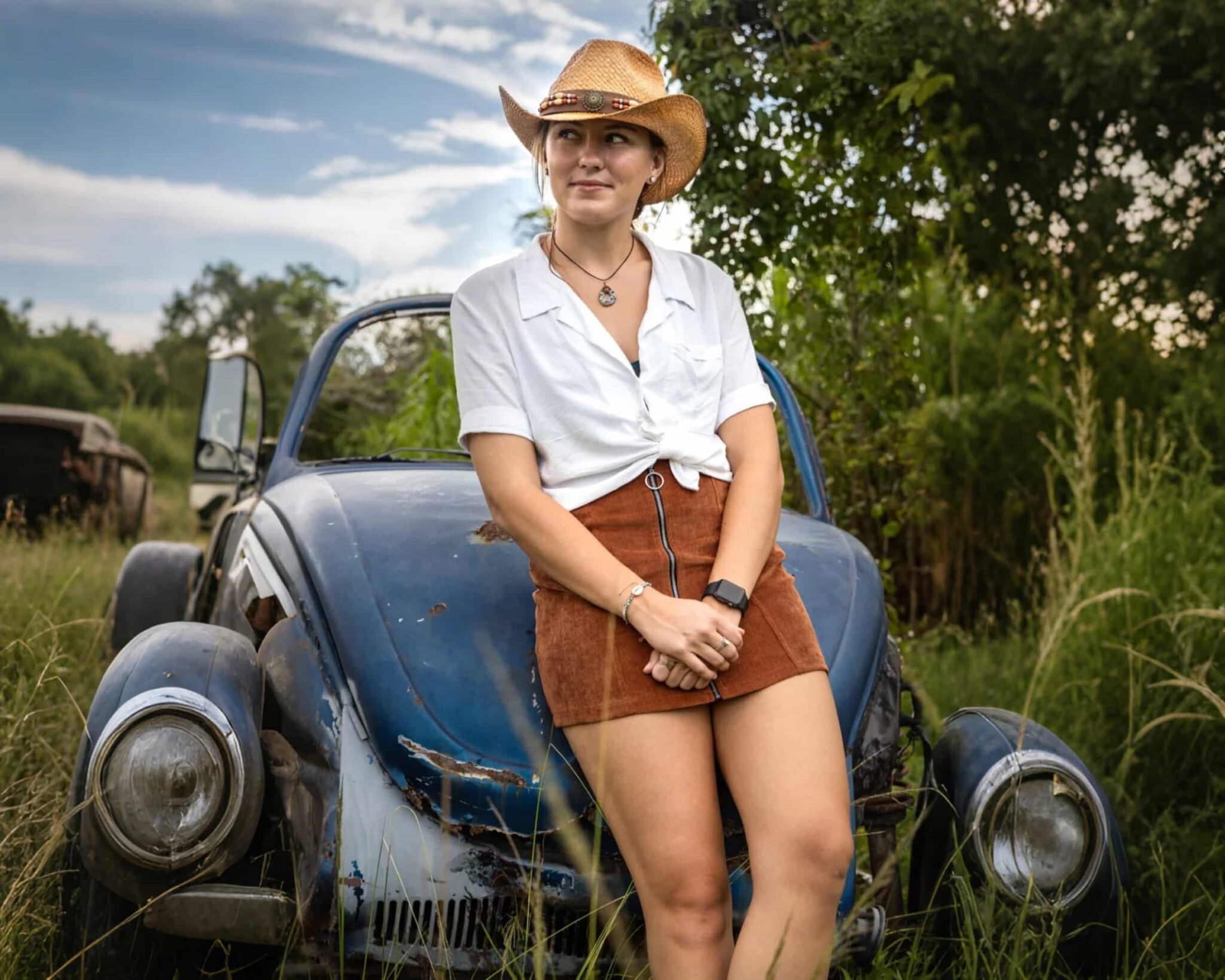 Woman in cowboy hat by vintage car.